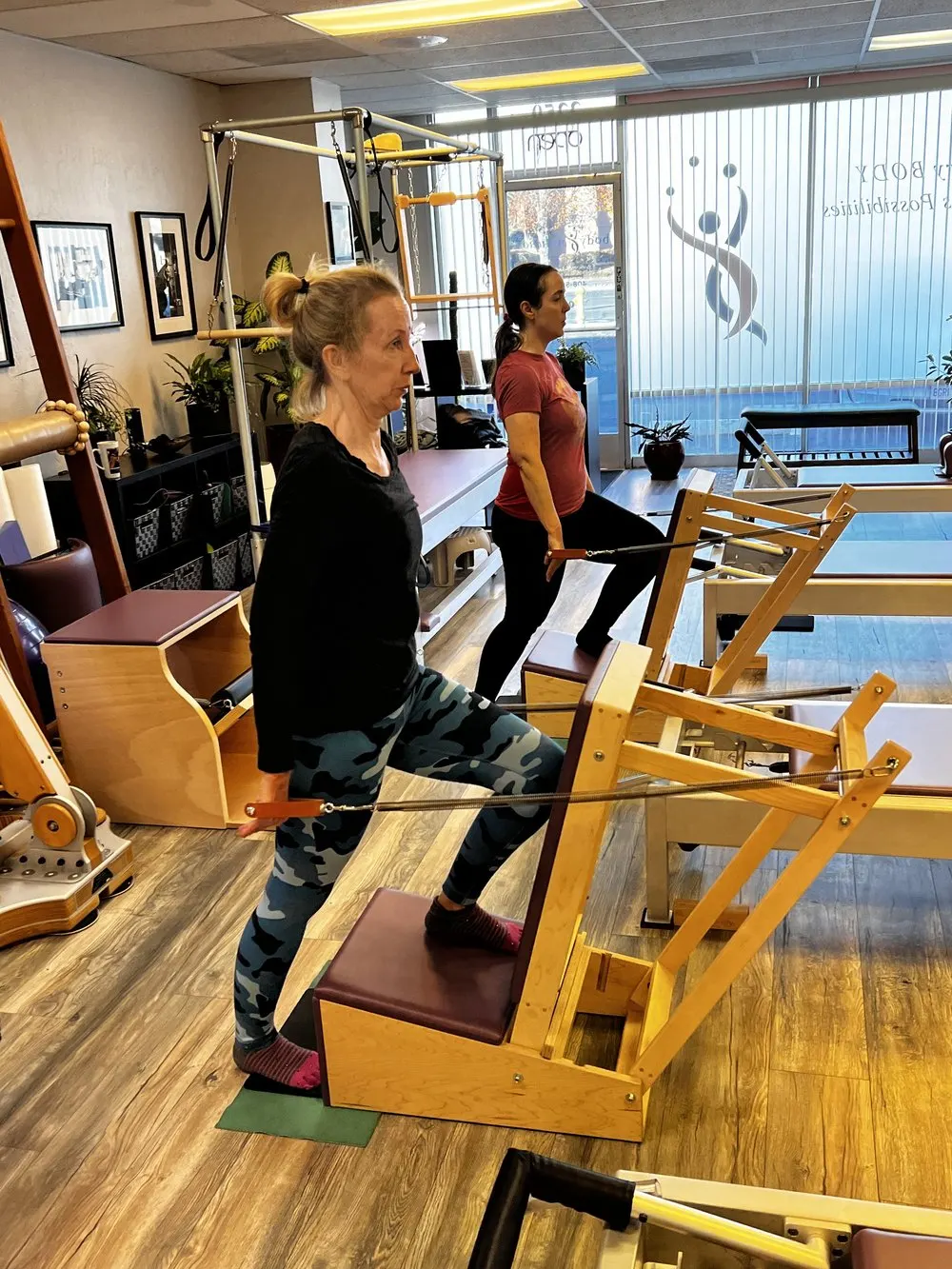 A student on the Pilates reformer with an instructor guiding the movement